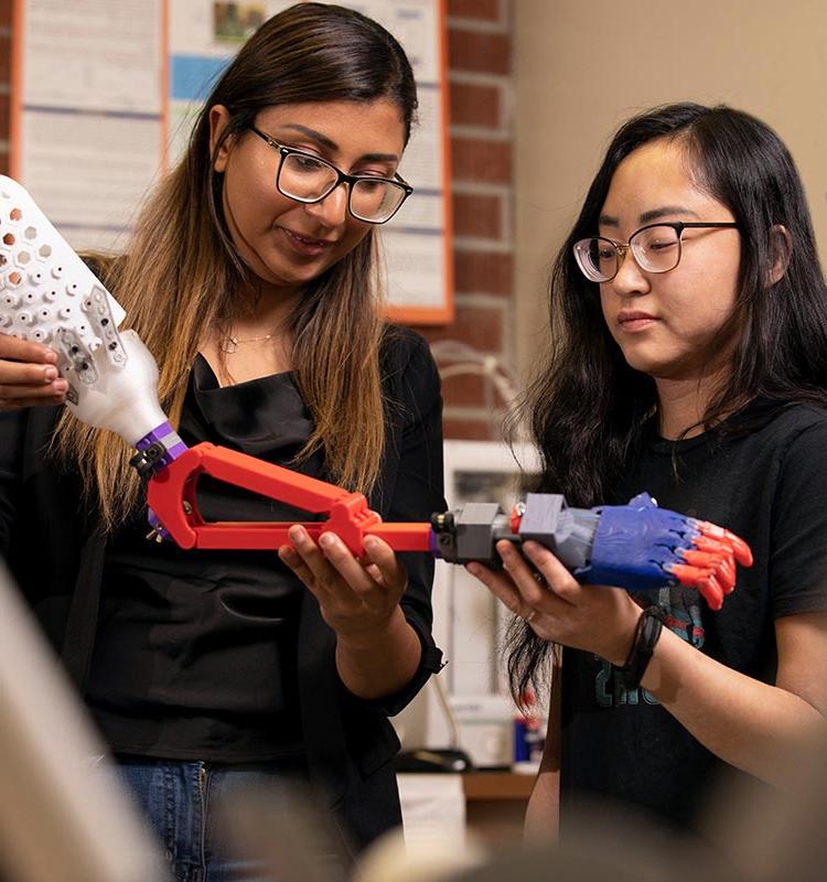 2 students examining 3D printed prosthetic arm